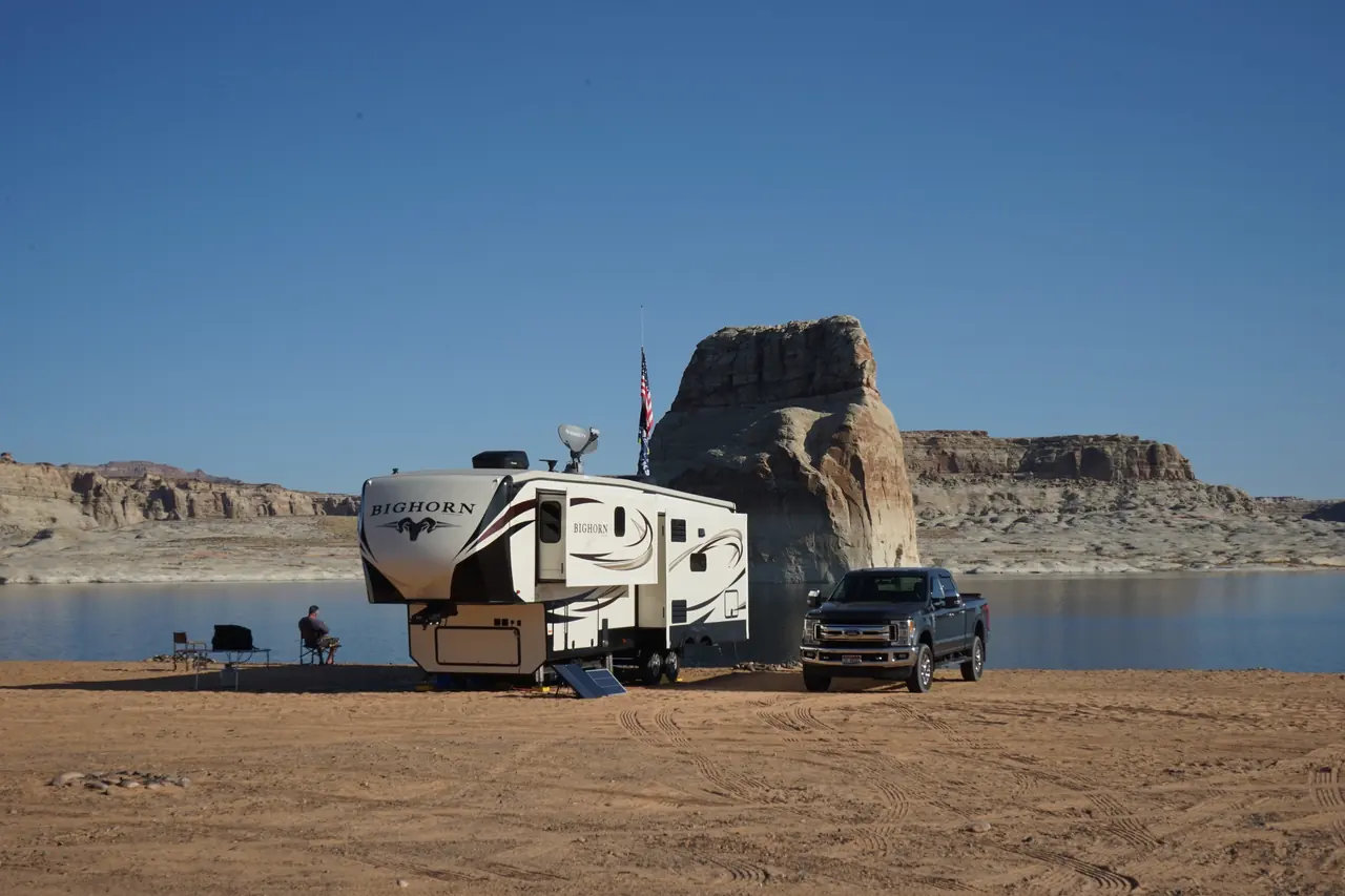 A motorhome parked near open water, showing the scale of a towed vehicle’s storage problem