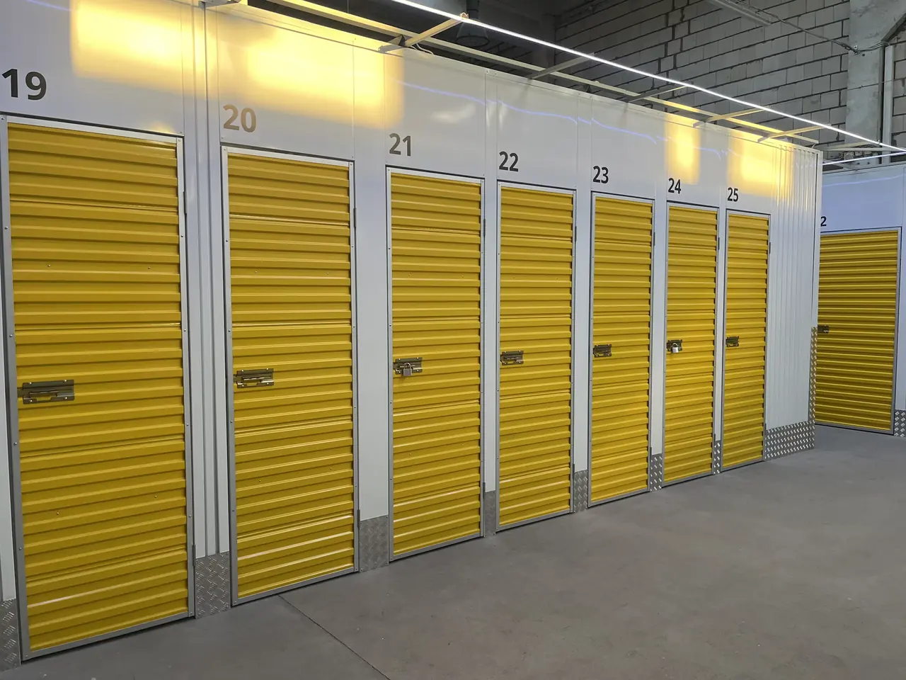 A row of small roll-up storage doors numbered along a wall
